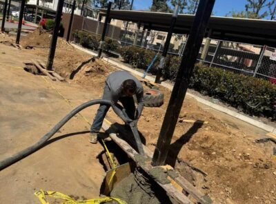 Construction worker pouring concrete at a site.